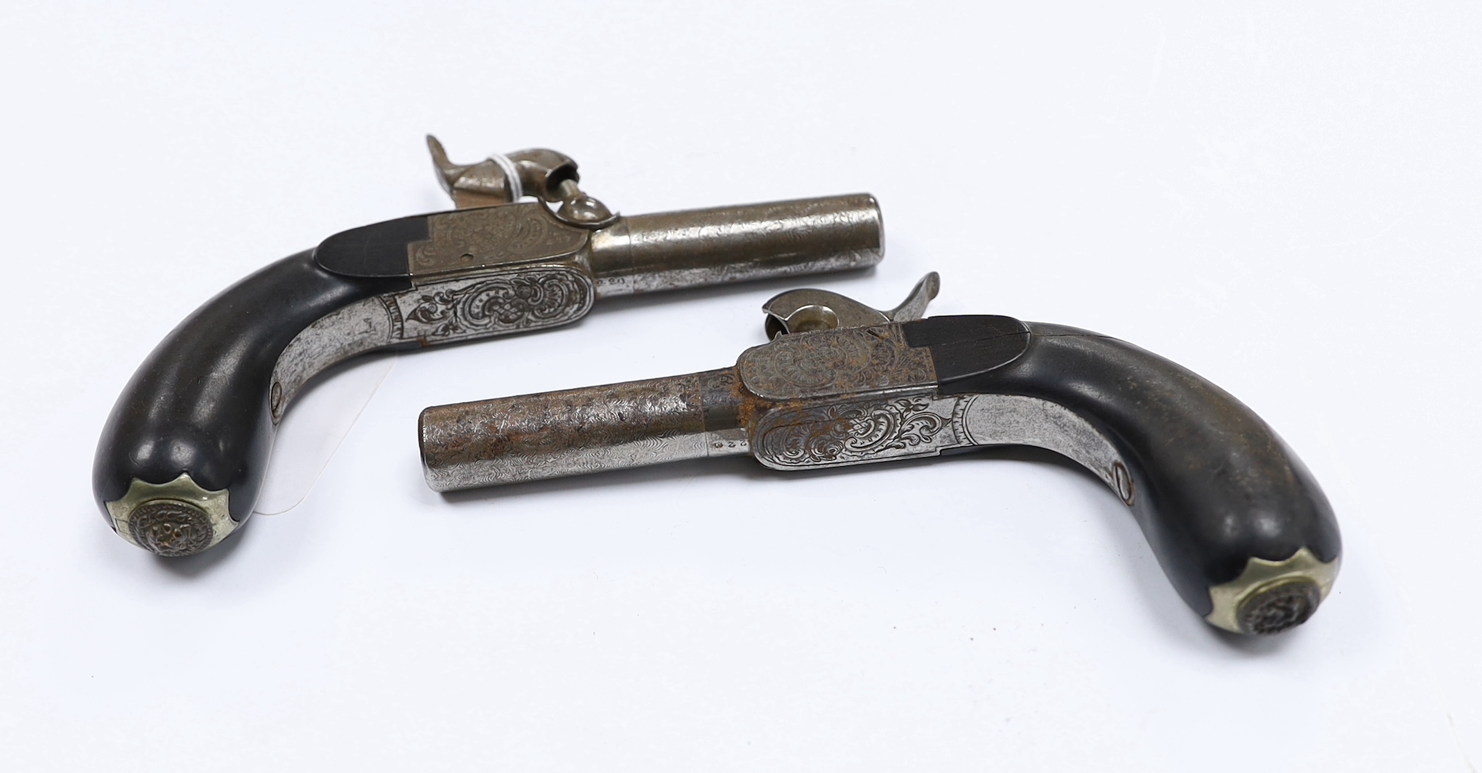 A pair of 19th century box lock, percussion pistols, with turn off Damascus twist barrels, engraved frames, folding triggers, and rounded ebony grips fitted with hinged butt cap lids, barrels 4.8cm